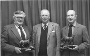 photo of farmers holding bronze trophies of a bull linking to more information