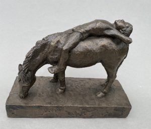 A bronze sculpture of a boy lying on a pony