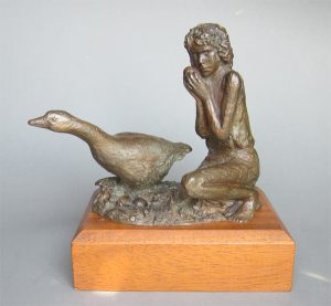 A small bronze sculpture of a goose and a girl holding an egg taken from its nest