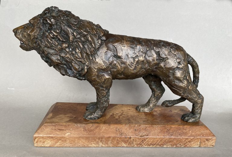 A bronze sculpture of a lion on a wooden base